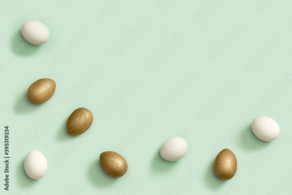 Painted Easter eggs white and gold colored on light green paper. Minimal easter concept. Top view spring holiday Painted Easter eggs white and gold colored on light green paper. Minimal easter concept. Top view spring holiday