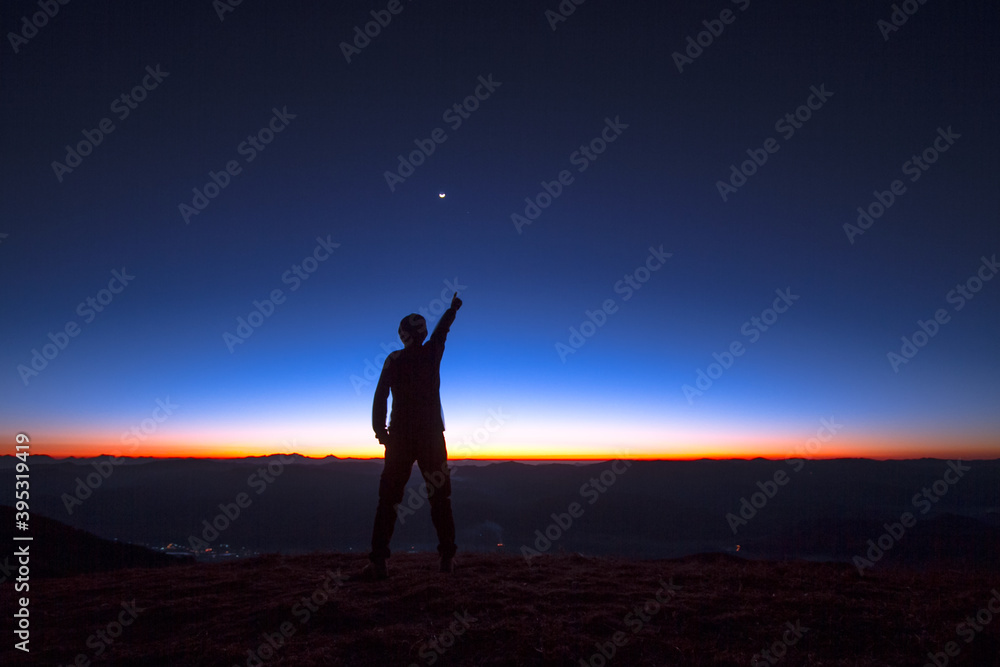 silhouette of a person on the top of mountain at sunset