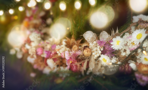 A Christmas garland of dried flowers on a Christmas tree with fairy lights and festive glowing bokeh background © Duncan Andison