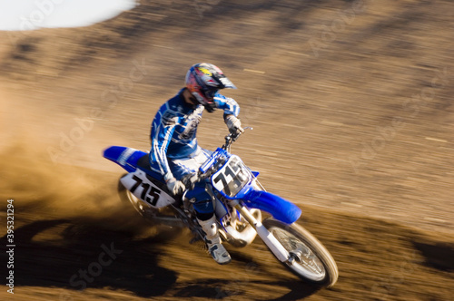 Fototapeta Naklejka Na Ścianę i Meble -  Motocross Racer Riding Motorcycle On Dirt Track