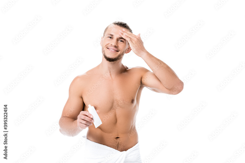 Fototapeta premium sexy shirtless man in towel applying face cream isolated on white