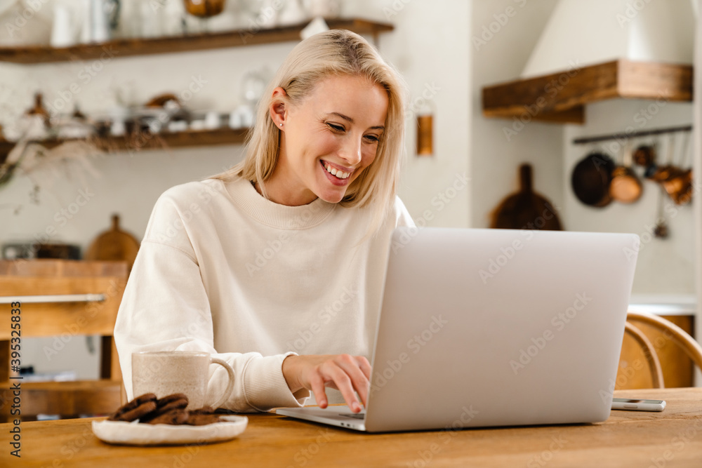 Beautiful happy woman drinking tea while working with laptop Beautiful happy woman drinking tea while working with laptop