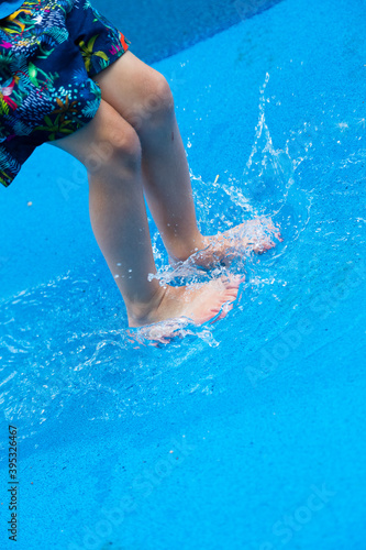 A child's feet land in a paddling pool creating a splash.