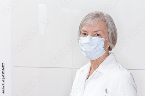 Senior female pharmacist with protective face mask, light background, copy or text space. photo