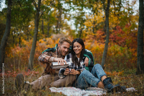 Young happy couple drinking tea and hugging while resting in forest © Drobot Dean