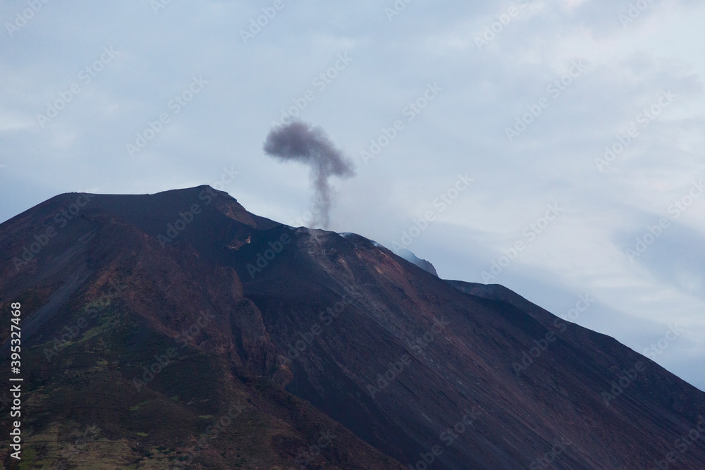 Sicily, Italy. A dark plume of volcanic smoke and ash rises from the active volcano of Stromboli.
