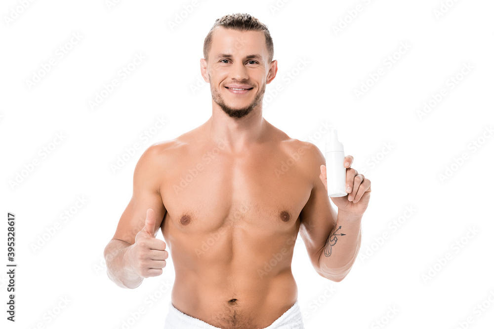 Fototapeta premium smiling shirtless man in towel holding foam and showing thumb up isolated on white