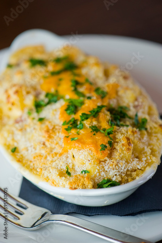 Potatoes au gratin. Potatoes baked in butter, cheese cream sauce, garnished with scallions, parsley and served in cast iron skillet. Classic American restaurant or French bistro side dish.