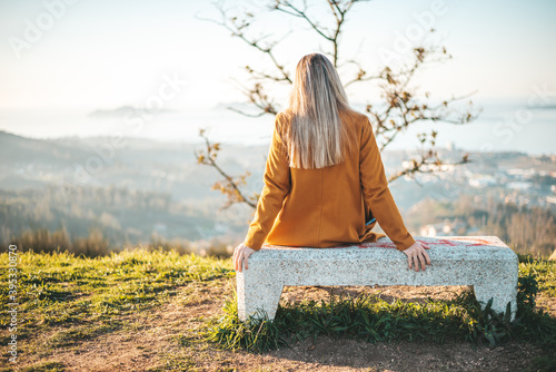 Wallpaper Mural Woman on a yellow coat sitting on a bench contemplating the landscape Torontodigital.ca