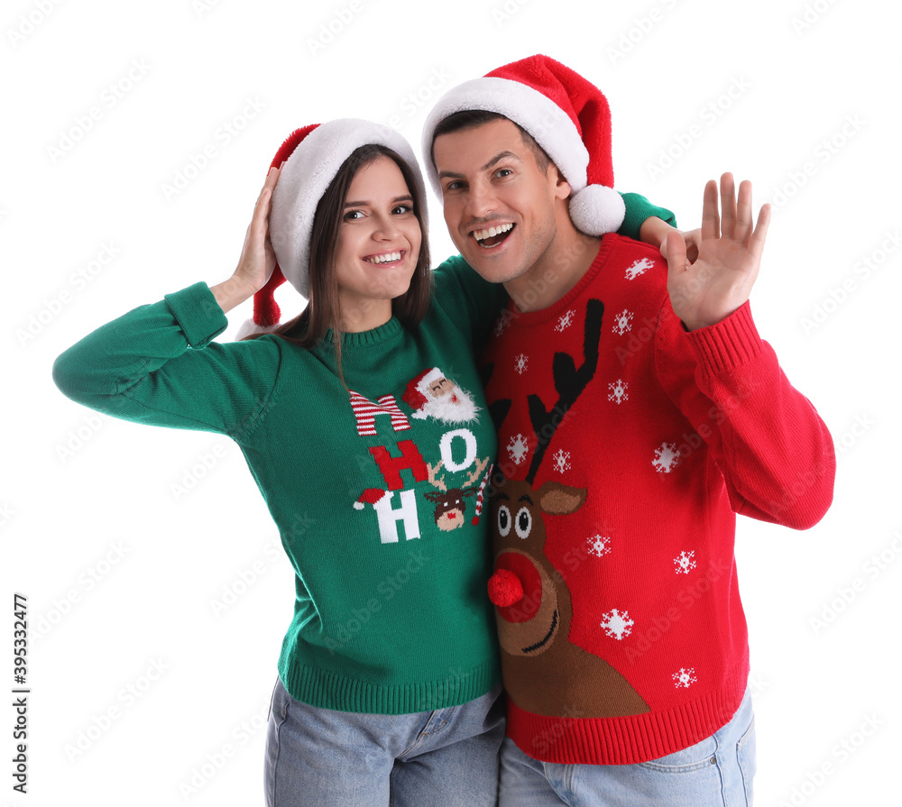 Beautiful happy couple in Santa hats and Christmas sweaters on white background Beautiful happy couple in Santa hats and Christmas sweaters on white background