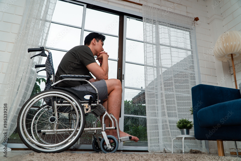 Obraz premium A disabled man sitting in a wheelchair is disappointed and Desperate to heal after car accident. Concept of Careless Driving, Insurance and Mental health care After the accident