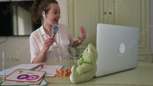 Young, attractive woman teaching English online to children. Singing ABC's with her students, using teaching props. Lesson, education, professional.