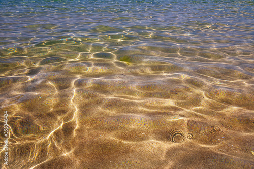 crystal clear sea water in shallow water with sun glare abstract background blur in motion