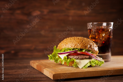 Two hamburgers and cola on the table over dark background Delicious fast food.