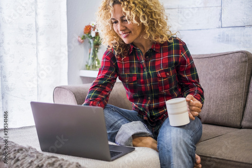 Beautiful portrait of woman work with laptop computer at home - shopping and job activity with online technology for free people - pretty female caucasian have relax on the sofa photo