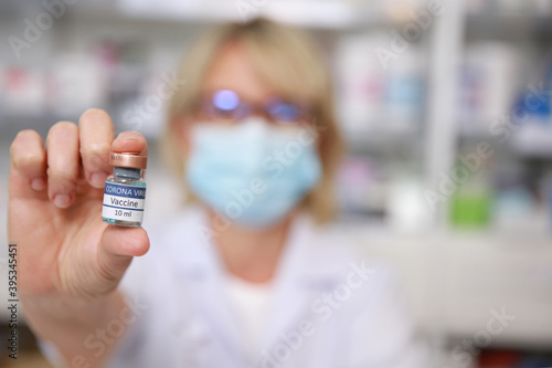 Female doctor with a stethoscope on shoulder holding syringe and COVID-19 vaccine. Healthcare And Medical concept, Close up bottle of vacine on hand