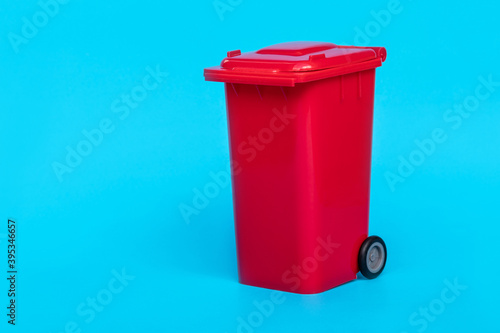 red wheelie waste bin on blue background.