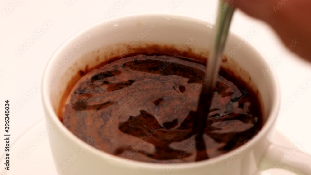 Close up hand stirring coffee in a cup with spoon. Hot Coffee Drink Concept. Close up hand stirring coffee in a cup with spoon. Hot Coffee Drink Concept.