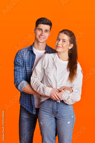 Young smiling man and woman in casual and denim hugging and looking at camera