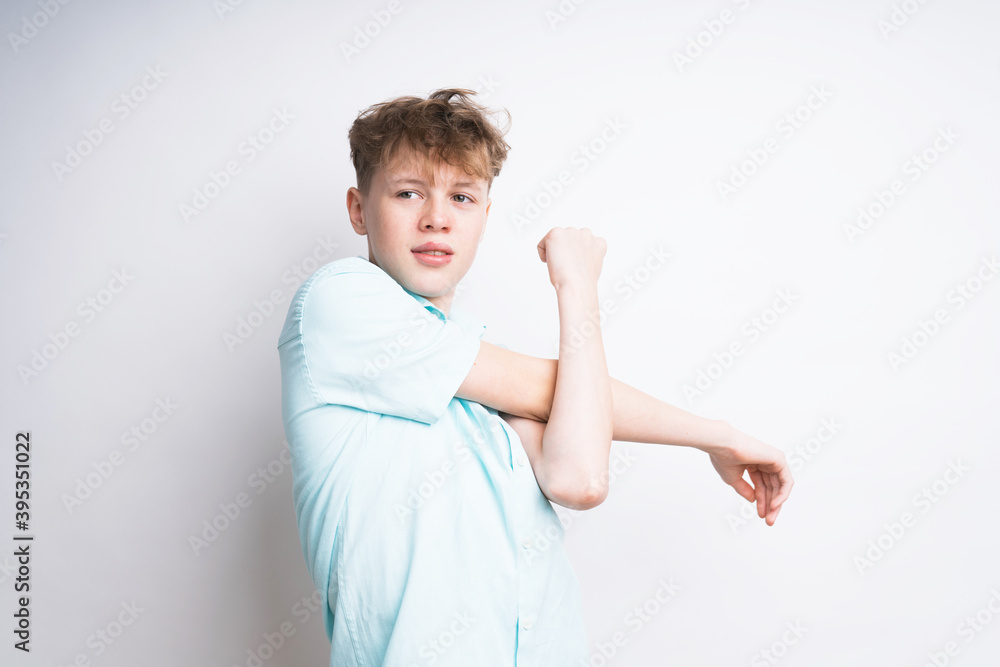 A caucasian teenage boy stretching his arm on a white backgorund A caucasian teenage boy stretching his arm on a white backgorund