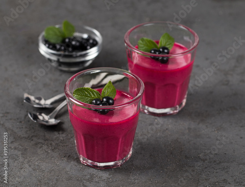 Dessert Panna Cotta cream with black currant in a glass on a dark gray background