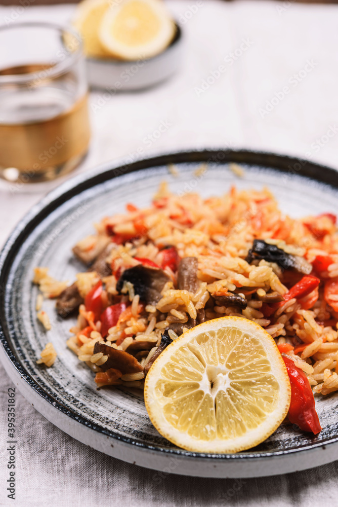 Arroz con verduras y azafran, spanish dish. Vegetarian risotto with vegetables, champignons and saffron on beige linen tablecloth. Selective focus Arroz con verduras y azafran, spanish dish. Vegetarian risotto with vegetables, champignons and saffron on beige linen tablecloth. Selective focus