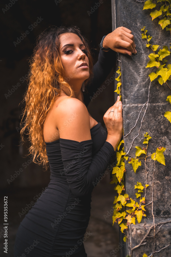 Lifestyle, wavy-haired Caucasian girl in a tight black dress. Relaxed an abandoned place full of nature Lifestyle, wavy-haired Caucasian girl in a tight black dress. Relaxed an abandoned place full of nature