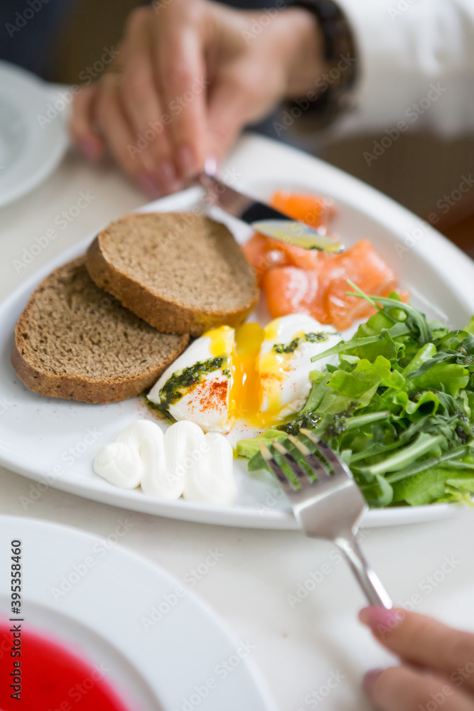Woman eating poached egg for breakfast