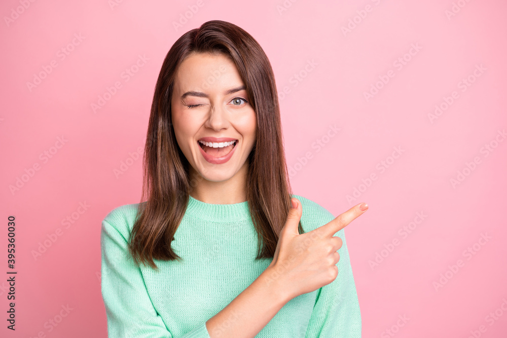 Photo of pretty flirty girl direct finger empty space close wink eye wear teal sweater isolated pink color background Photo of pretty flirty girl direct finger empty space close wink eye wear teal sweater isolated pink color background