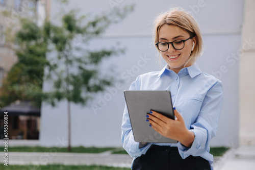 Photos Smiling woman in eyewear using tablet outdoors