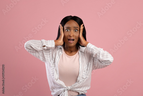No way. Shocked black woman grasping her head in disbelief over pink studio background
