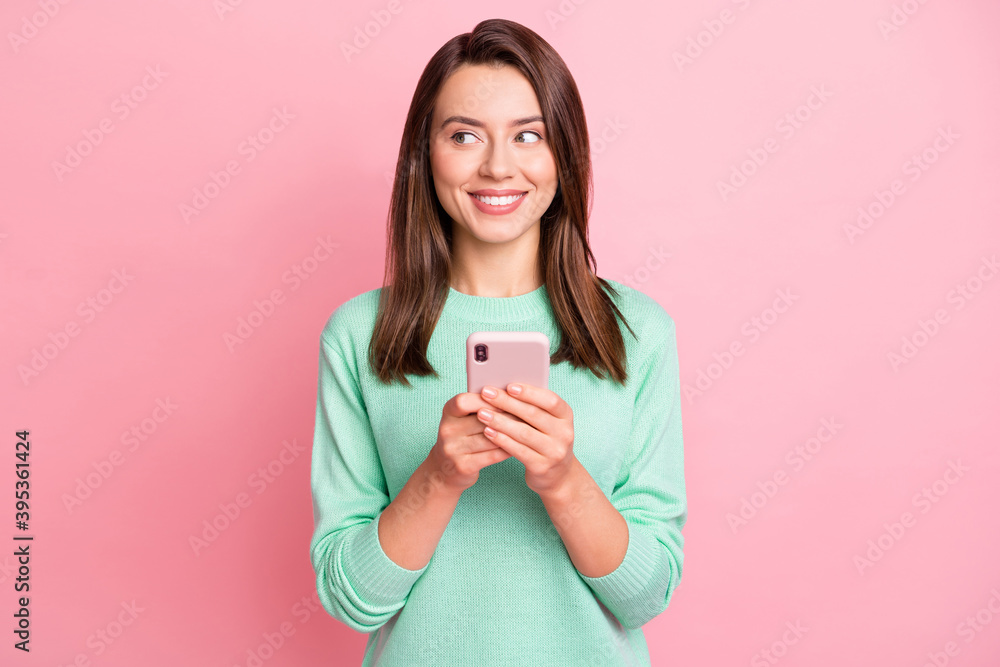 Portrait of pretty cheerful person arm hold phone looking empty space wear pullover isolated on pink color background