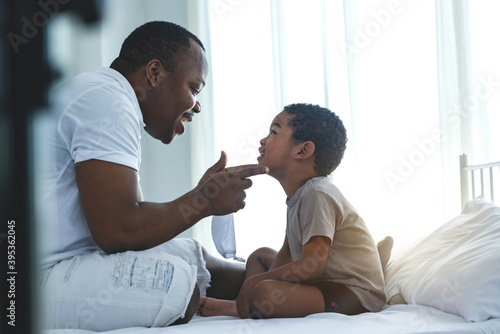 African dads help his son wearing medical mask for protection Covid-19, teaching to wear mask properly, How to wear face mask, prevent corona virus