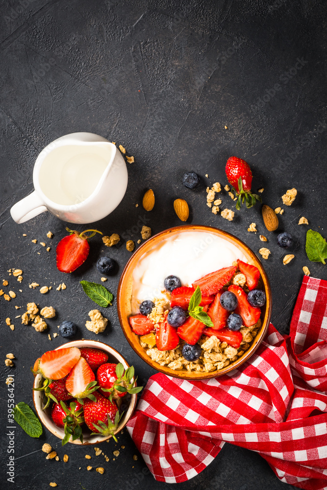 Yogurt granola with fresh berries on black stone table. Top view with copy space. Healthy food, snack or breakfast.