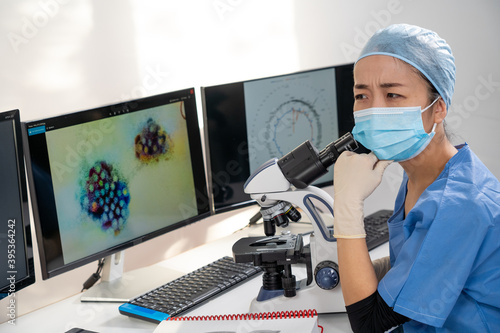 Femme m  decin asiatique regarde au microscope des images m  dicales du covid-19 et de scanner des poumons infect  s.