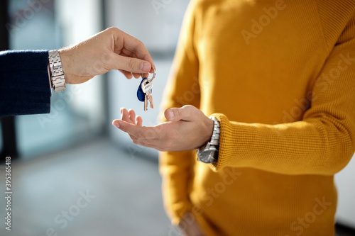 Close-up a real estate agent giving new house key to his client.