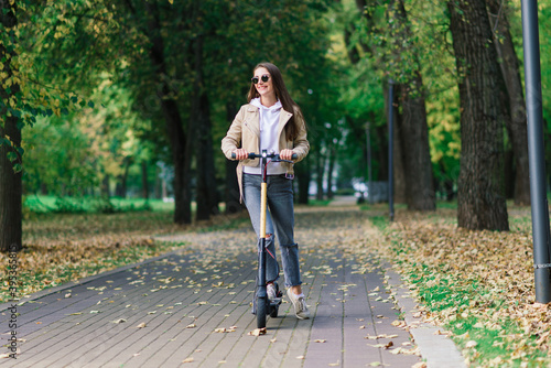 Young woman riding an electric scooter in an autumn park. Green transport, traffic jam problems. © Ivan Zelenin