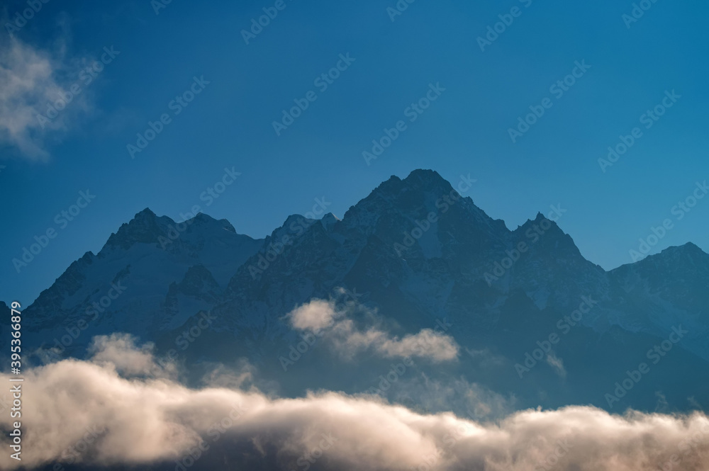 Rocks behind clouds in North Caucasus mountains in autumn on sunny day