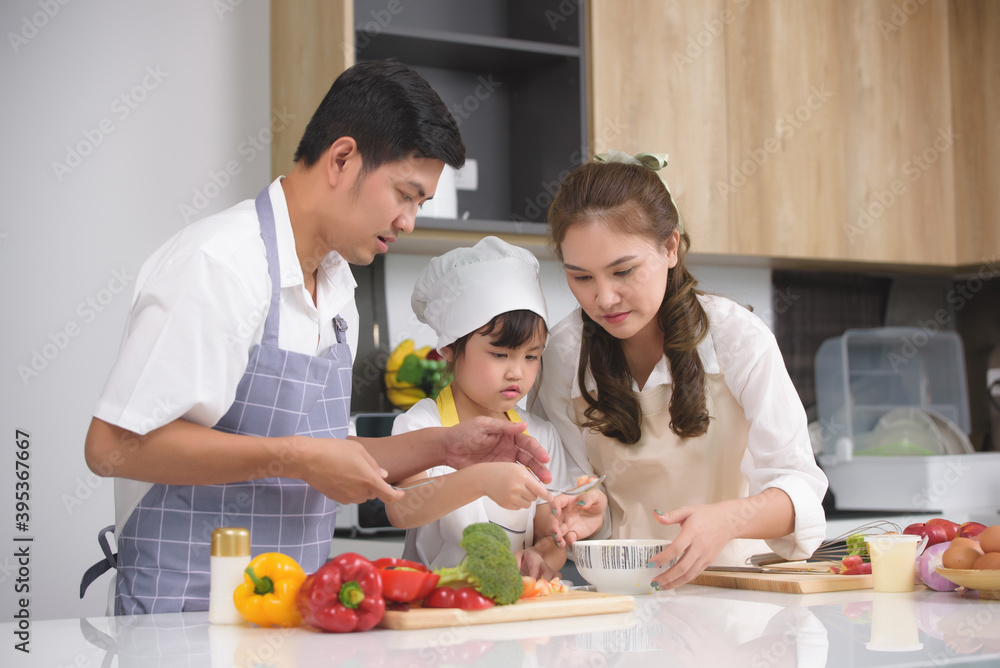 Asian family enjoy with cooking together salad foods homemade in kitchen room at modern home. Create activities together in the family. Focusing on center girl children.