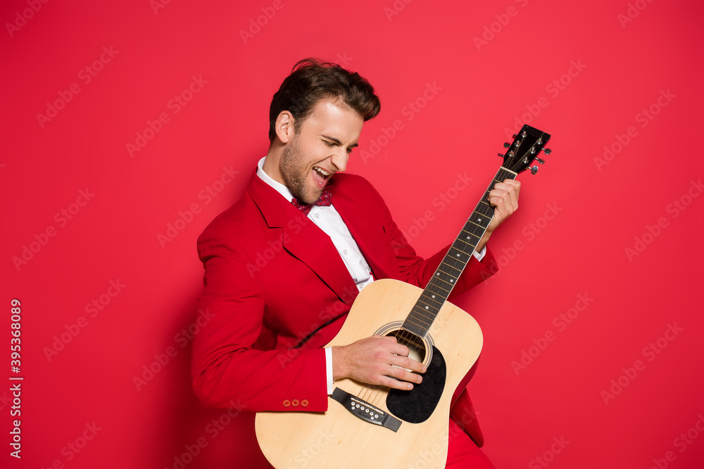 Naklejka premium man in red suit playing acoustic guitar on red background
