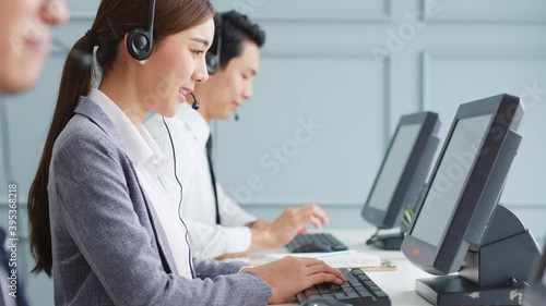 Asian call center team, customer service, telesales in formal suit wearing headset or headphone talking with customer in modern office photo