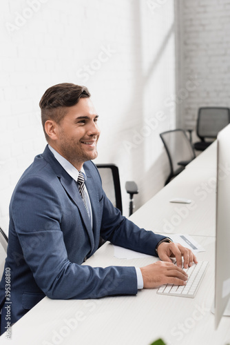  businessman typing on computer keyboard, while sitting at workplace in office