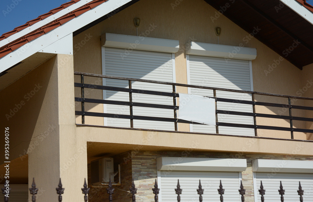 Obraz premium A exterior view of large attic, loft windows closed with pvc motorized window roller shutters leading to the open balcony of a house.