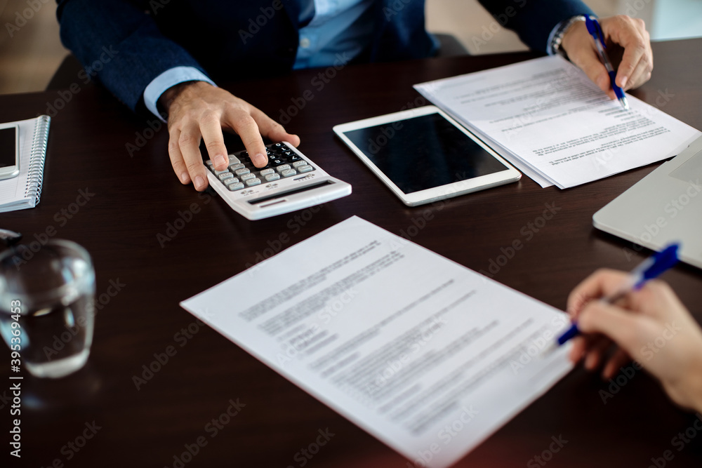 Close-up of financial consultant going through paperwork on a meeting with a client. Close-up of financial consultant going through paperwork on a meeting with a client.