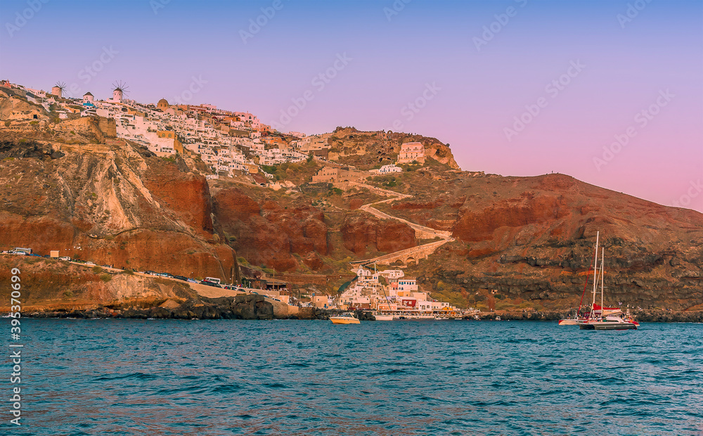 A view towards Amoudi Bay and Oia as the sun sets in Santorini on a summers evening