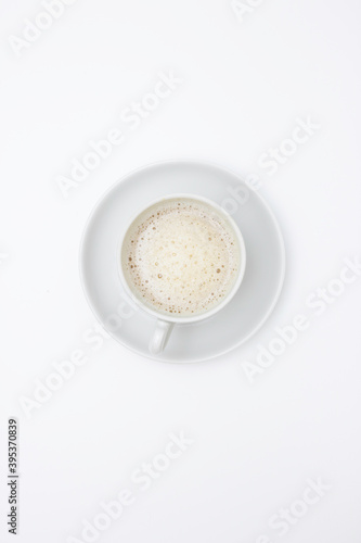 White Cup and saucer with cappuccino and white foam. Top view, white background. Free space for text.
