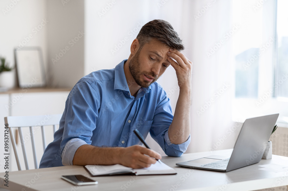 Busy Businessman Taking Notes To Notepad While Working With Laptop At Office Busy Businessman Taking Notes To Notepad While Working With Laptop At Office