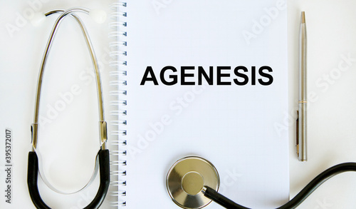 In the notebook is the text of AGENESIS, next to the stethoscope and pen. photo