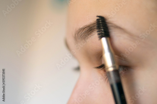 Close-up of the eyebrow of the girl she will be combing with the eyebrow brush.