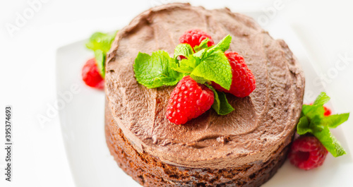 Gluten free tasty round cake based on Belgian chocolate decorated with fresh raspberries and mint